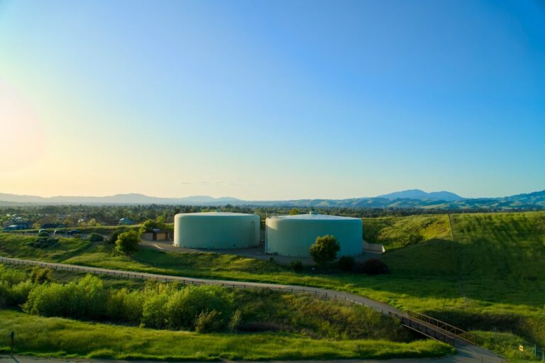 Two water tanks sit on a hill under the sky